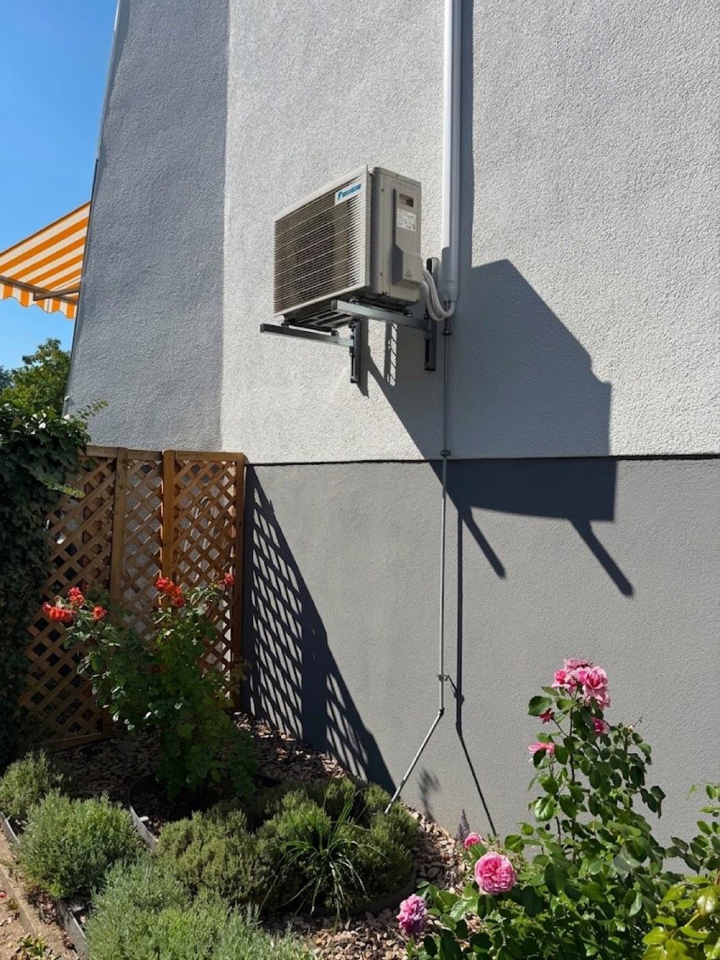 Daikin-Außeneinheit, sauber an der Hausfassade über dem Garten montiert