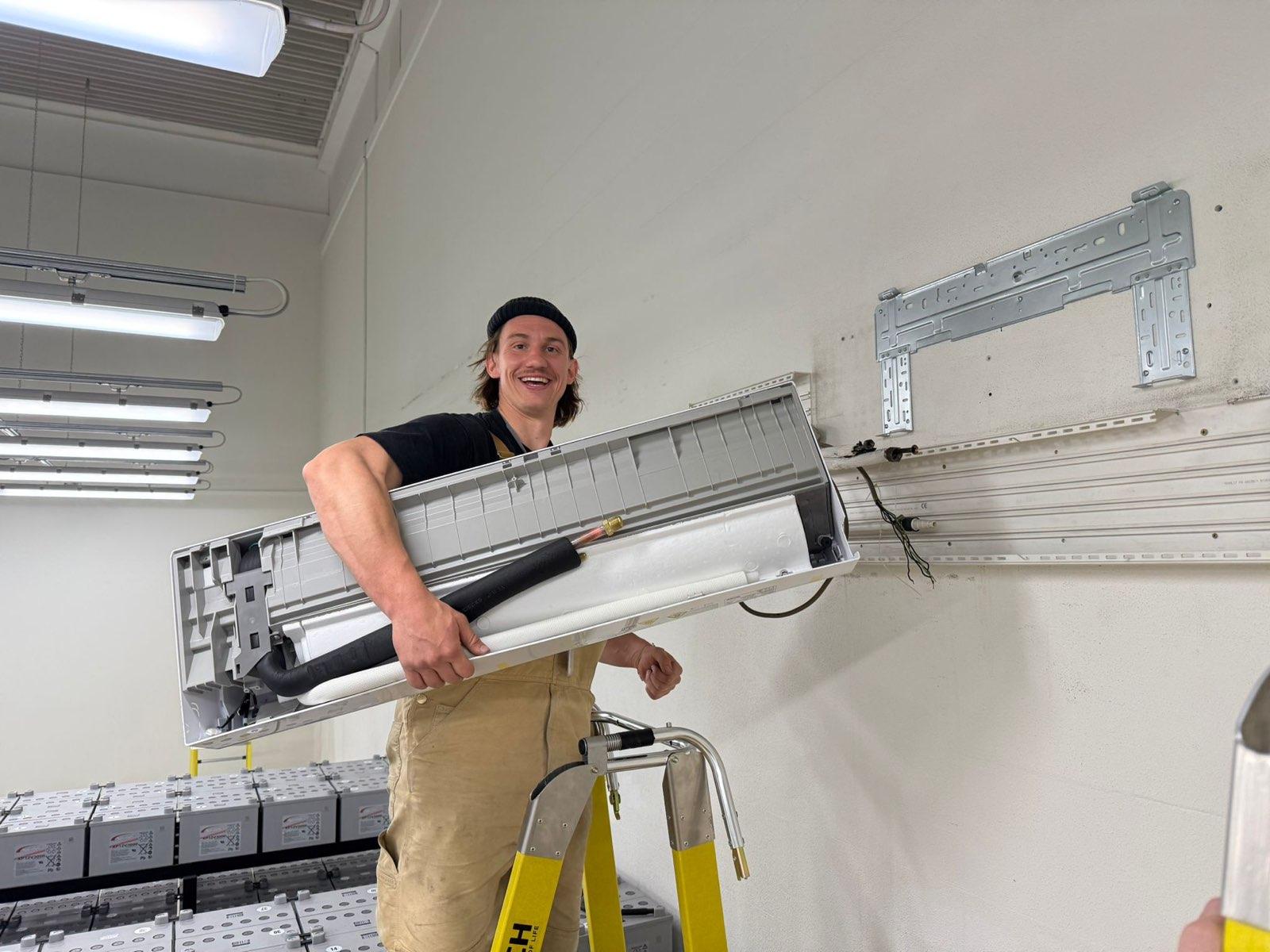 Monteur setzt ein Innengerät an die Wand eines Technikraums
